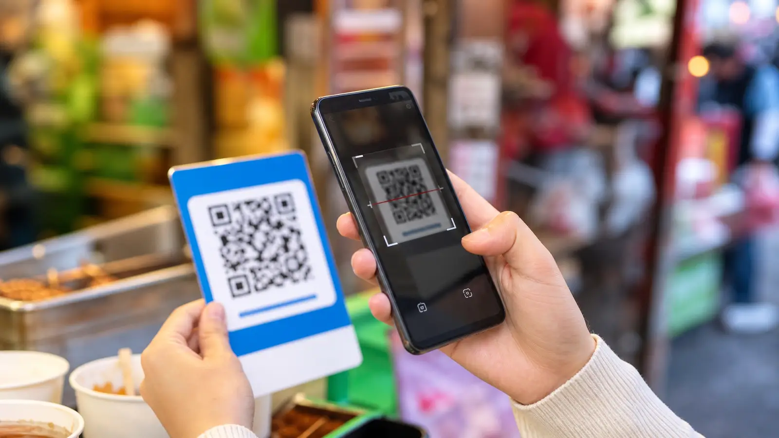 A foreign traveller paying with a QR code on a smartphone at a street stall in China
